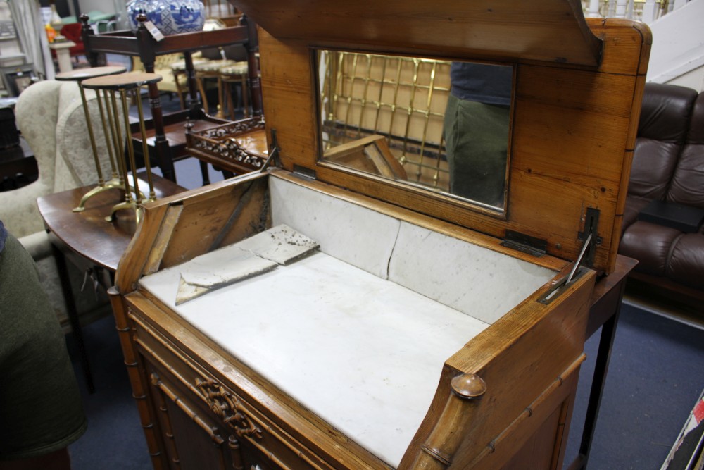 An Edwardian pine washstand, the rising top opening to reveal marble lined interior and mirror, over a drawer and bamboo moulded cupboa